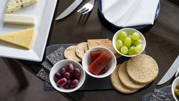 Una tabla con diversos quesos, uvas y galletas.