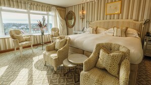 Un dormitorio amplio con una cama grande, una araña, vistas de la ciudad y muebles con estampado de leopardo.