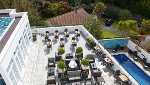 Una terraza al aire libre con varias zonas de estar, piscina y vistas del paisaje circundante.