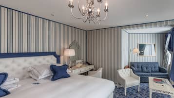 Een hotelkamer met een groot bed, een bureau, een stoel, een bank en een kroonluchter.
