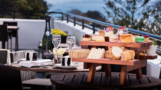 Una mesa de picnic de madera con diversos alimentos y una botella de champán Lanson.