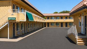 Un motel con un patio central, varias habitaciones con balcones y un letrero de la oficina.