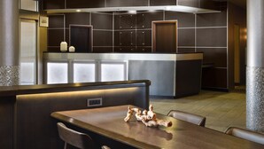 A modern hotel lobby with a reception desk, seating area, and a large mirror.