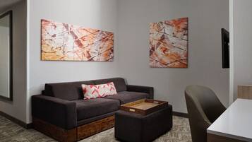 Un salon moderne avec un canapé gris foncé, une table basse en bois et deux tableaux abstraits accrochés au mur.