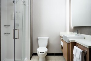 Une salle de bain moderne avec une douche à parois de verre, des toilettes blanches et un meuble-lavabo avec un miroir et un évier.