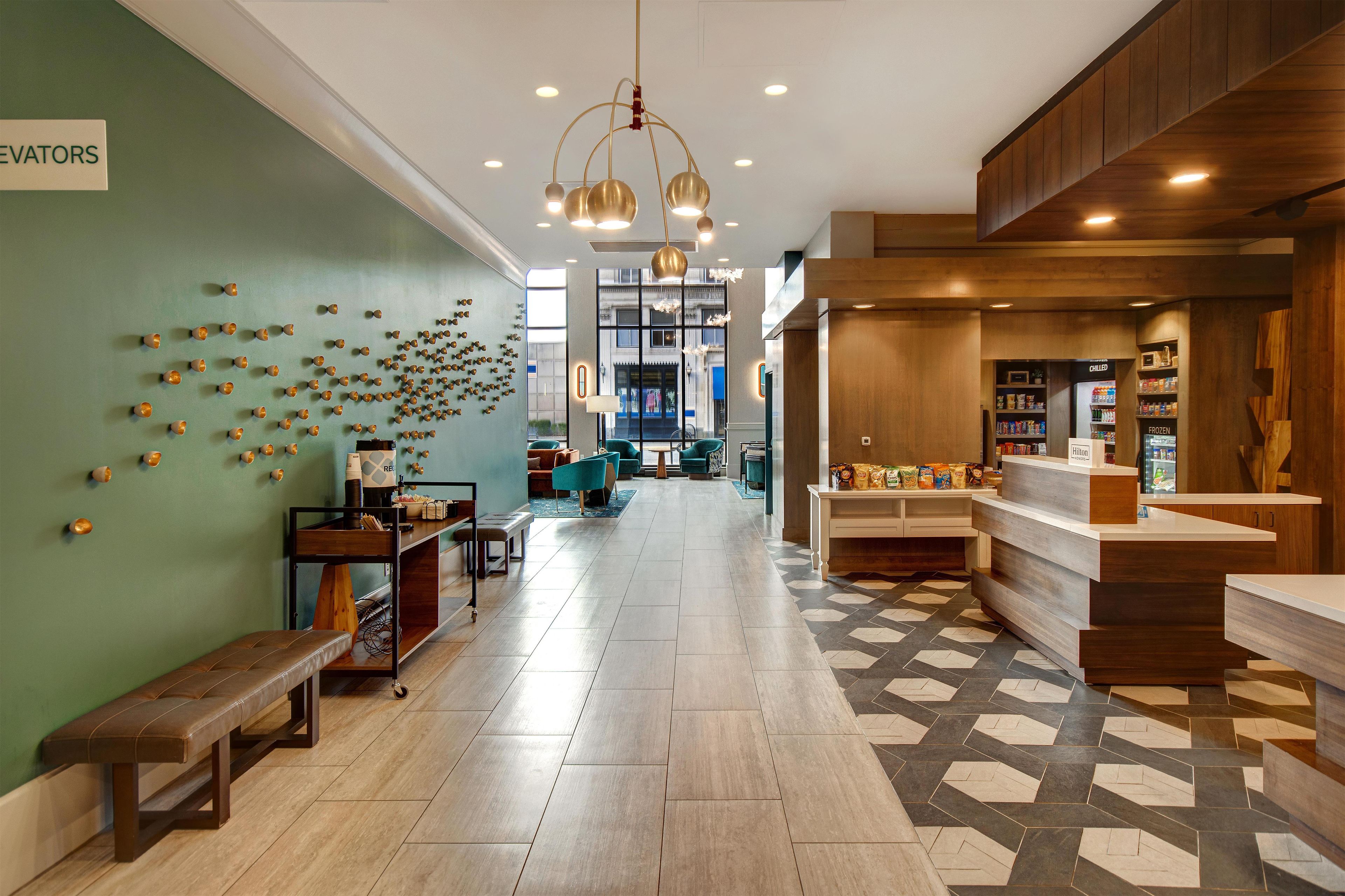 A hotel lobby with a reception desk, seating area, and a wall with decorative elements.