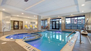 Une piscine intérieure à l’eau claire, dotée d’un plongeoir et d’un sol carrelé.