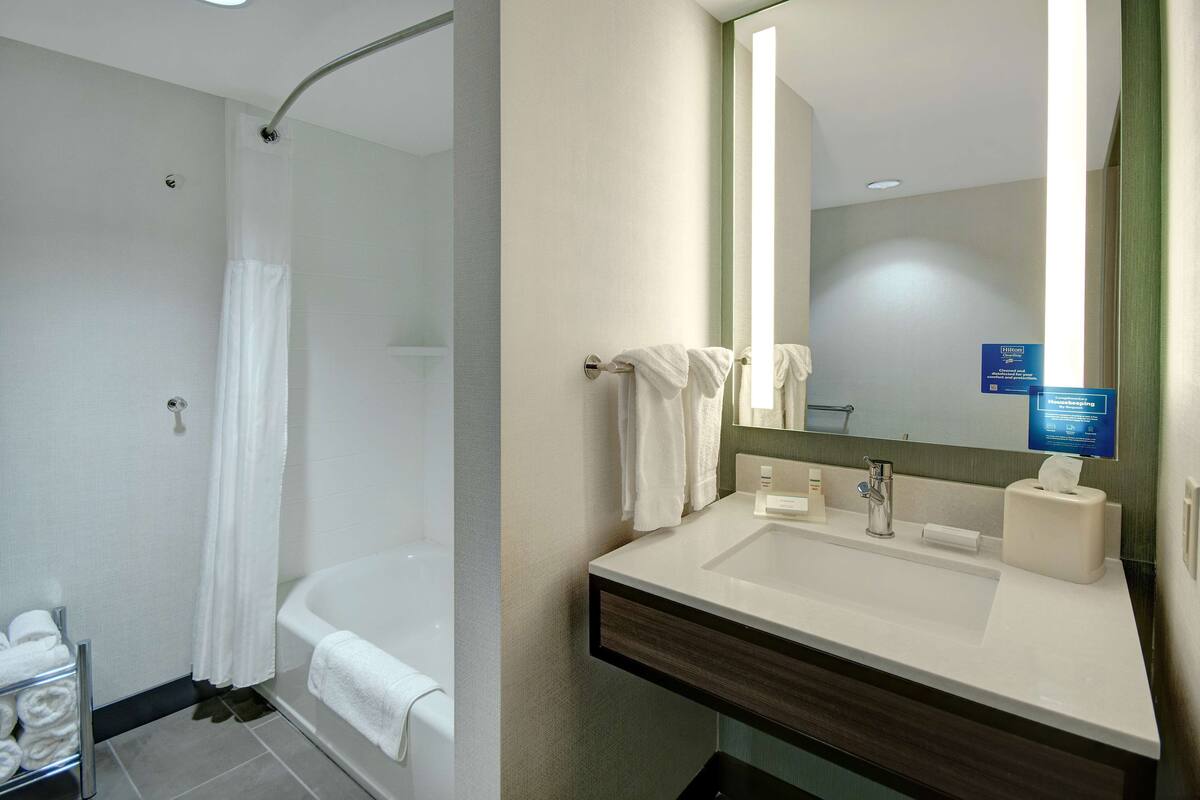 A modern bathroom with a bathtub, a shower area, and a sink with a mirror.