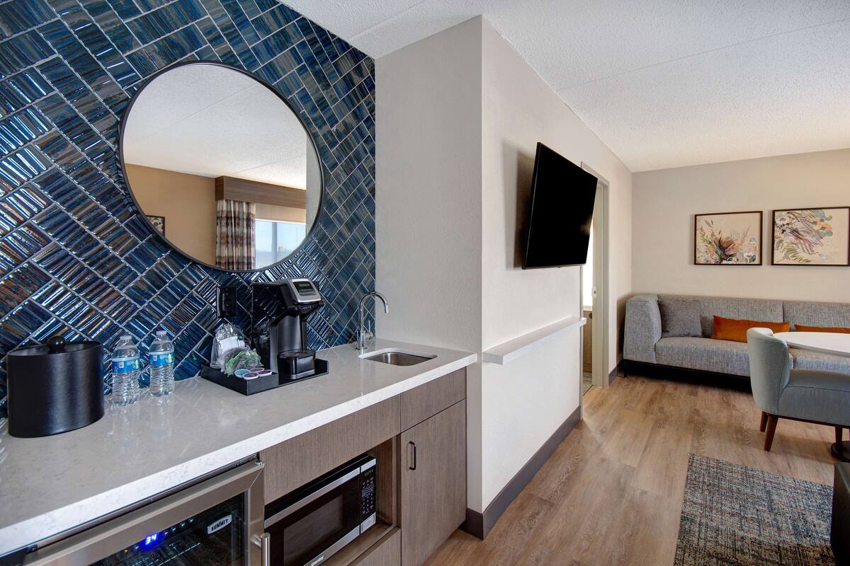A modern kitchen with a large mirror, a coffee maker, and a built-in microwave.