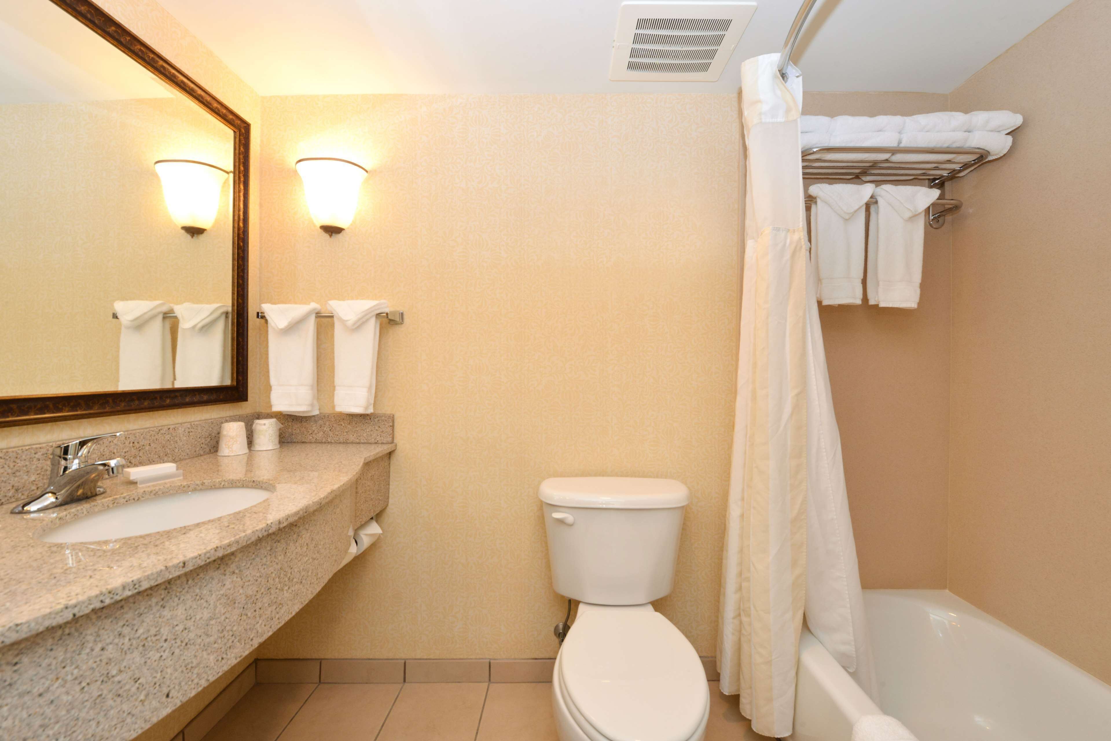 A bathroom with two sinks, a toilet, a shower with a curtain, and a towel rack with towels.