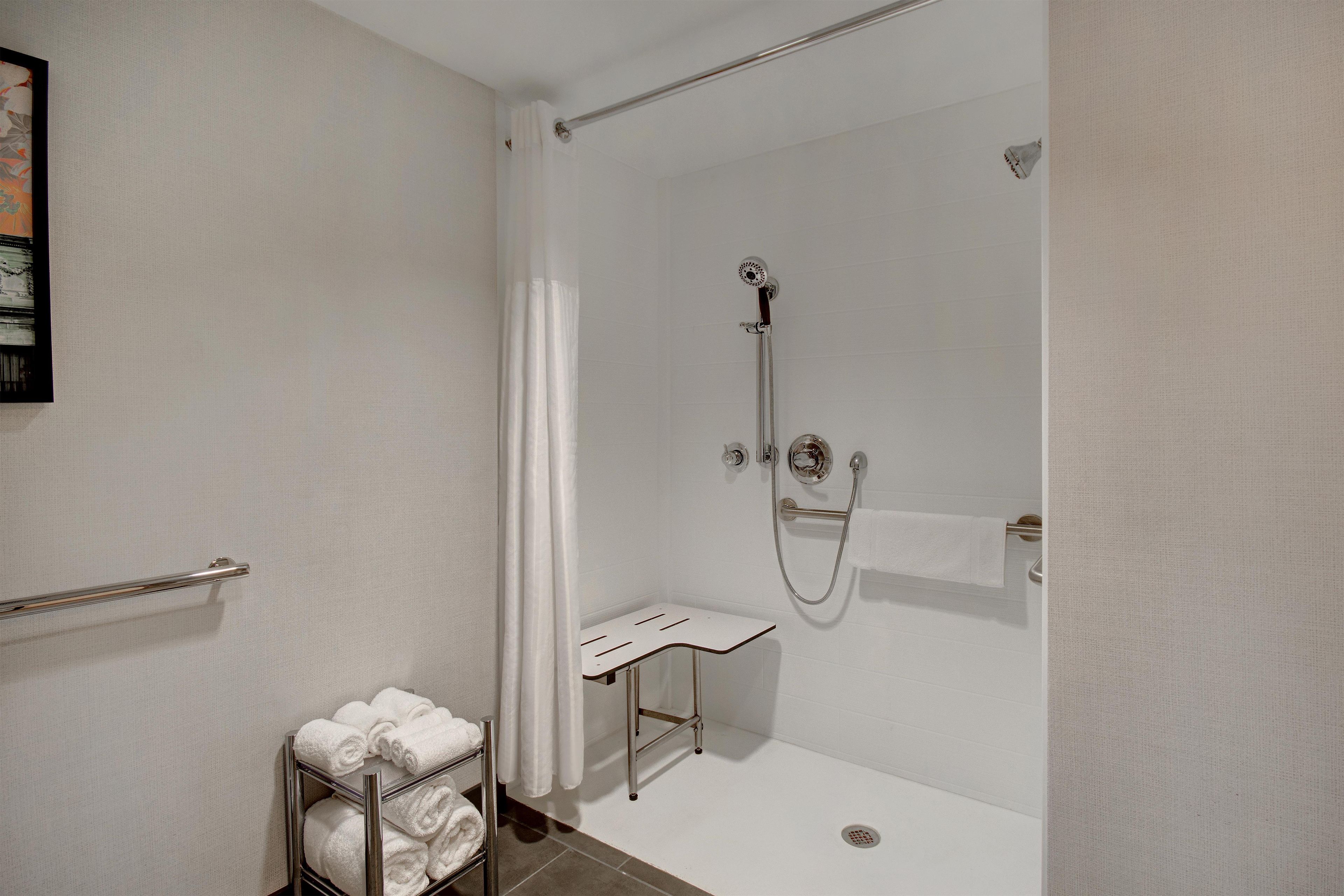 A modern bathroom with a glass-enclosed shower, a towel rack, and a small shelf.
