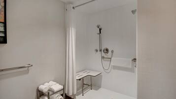 A modern bathroom with a glass-enclosed shower, a towel rack, and a small shelf.