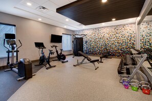 A gym with cardio machines, weightlifting equipment, and a patterned wall.