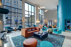 A modern hotel lobby with large windows, a central seating area, and a view of the cityscape.
