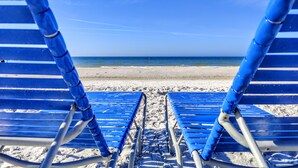 Une plage avec deux chaises bleues donnant sur l’océan.