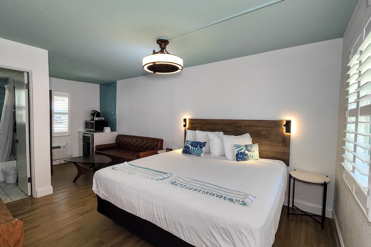 A bedroom with a large bed, a wooden headboard, a ceiling fan, and a small table.