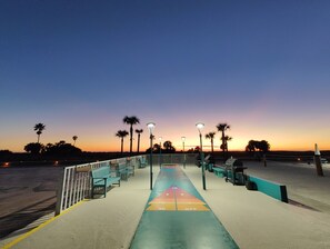 Un paseo marítimo con bancos y farolas que conduce a una playa con palmeras.