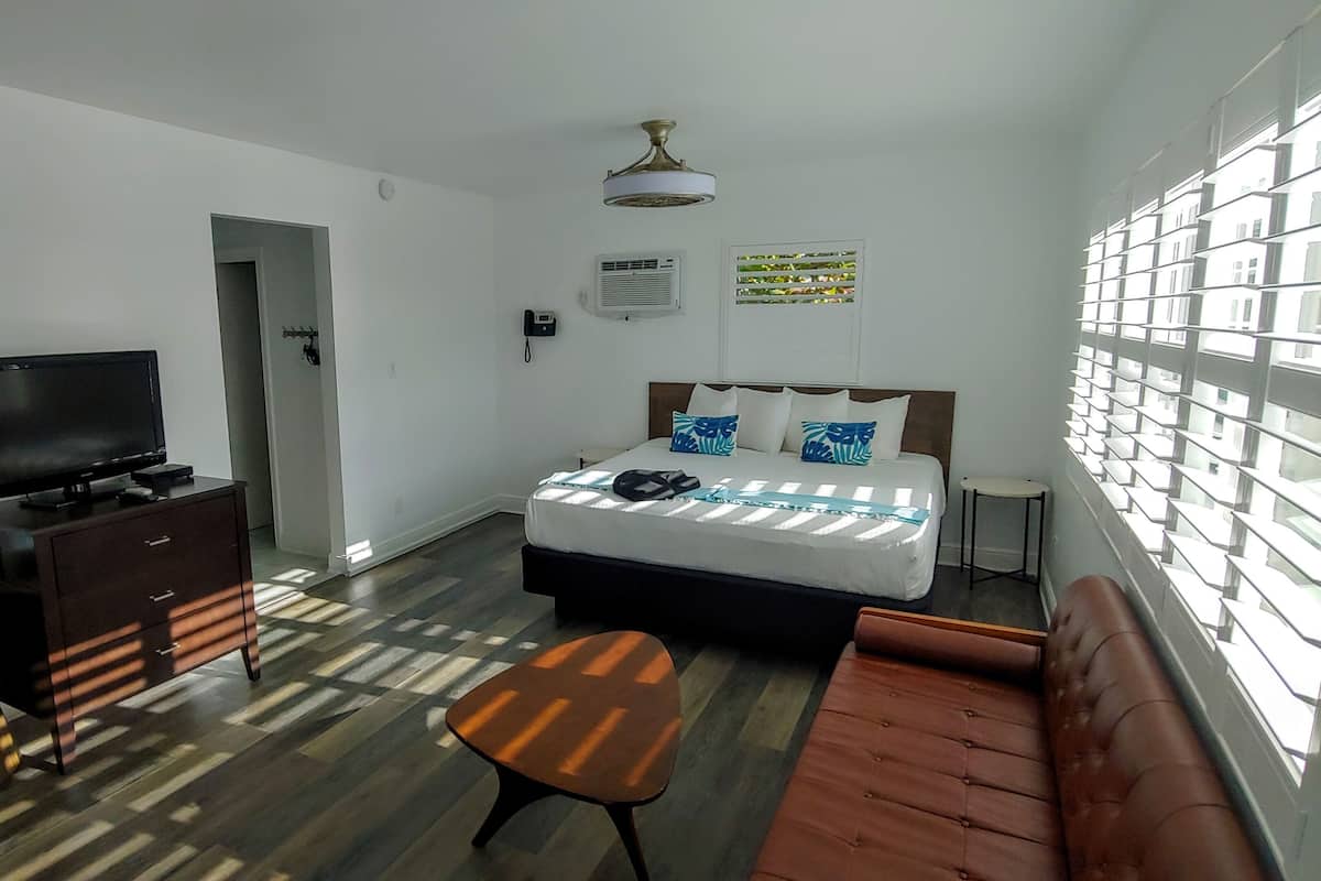 A hotel room with a bed, a TV, a desk, a chair, and a sofa.