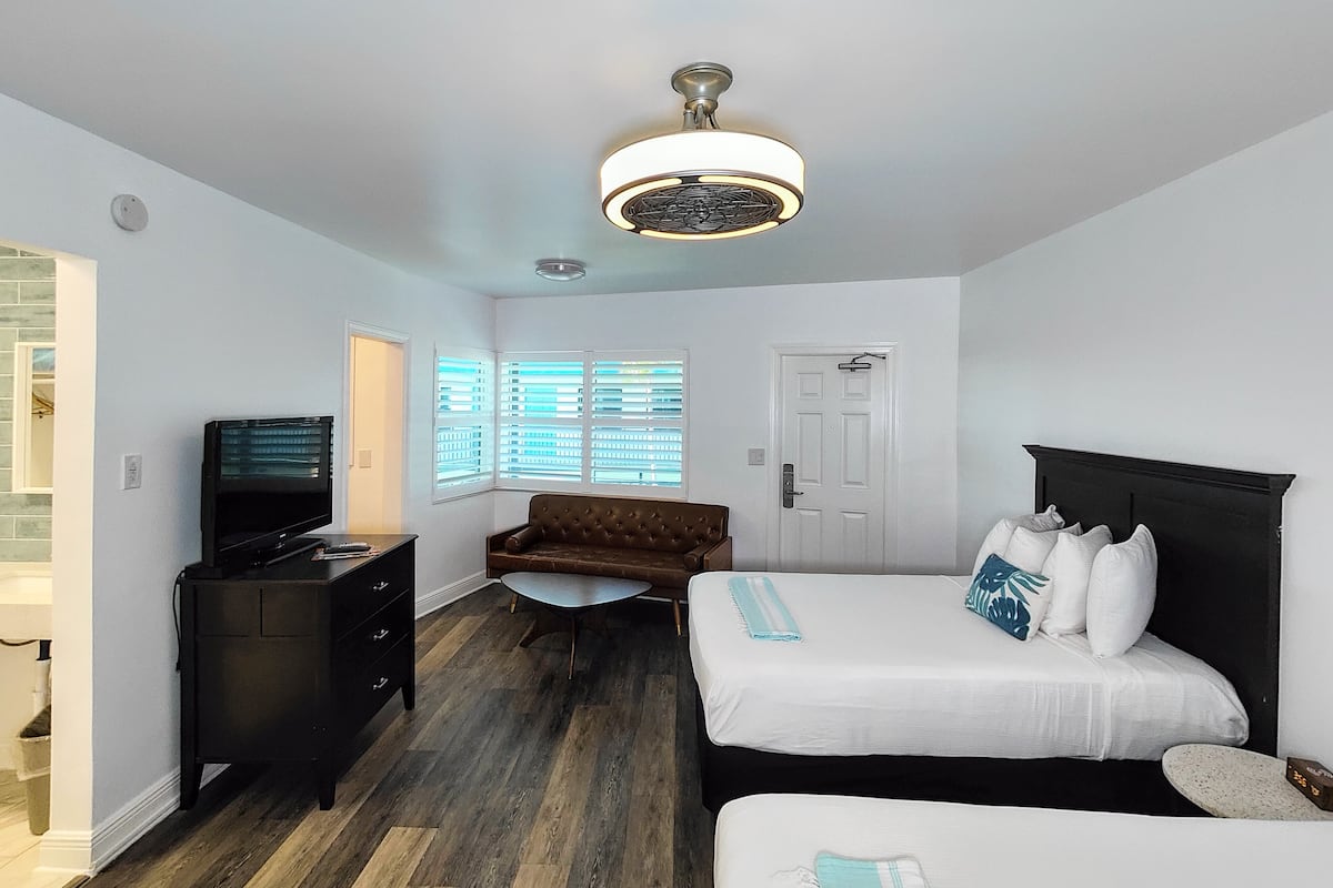A hotel room with a bed, a sofa, a desk, and a television.