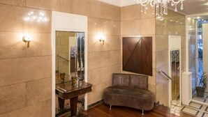 Un vestíbulo amplio con candelabro, zona de estar y espejo.