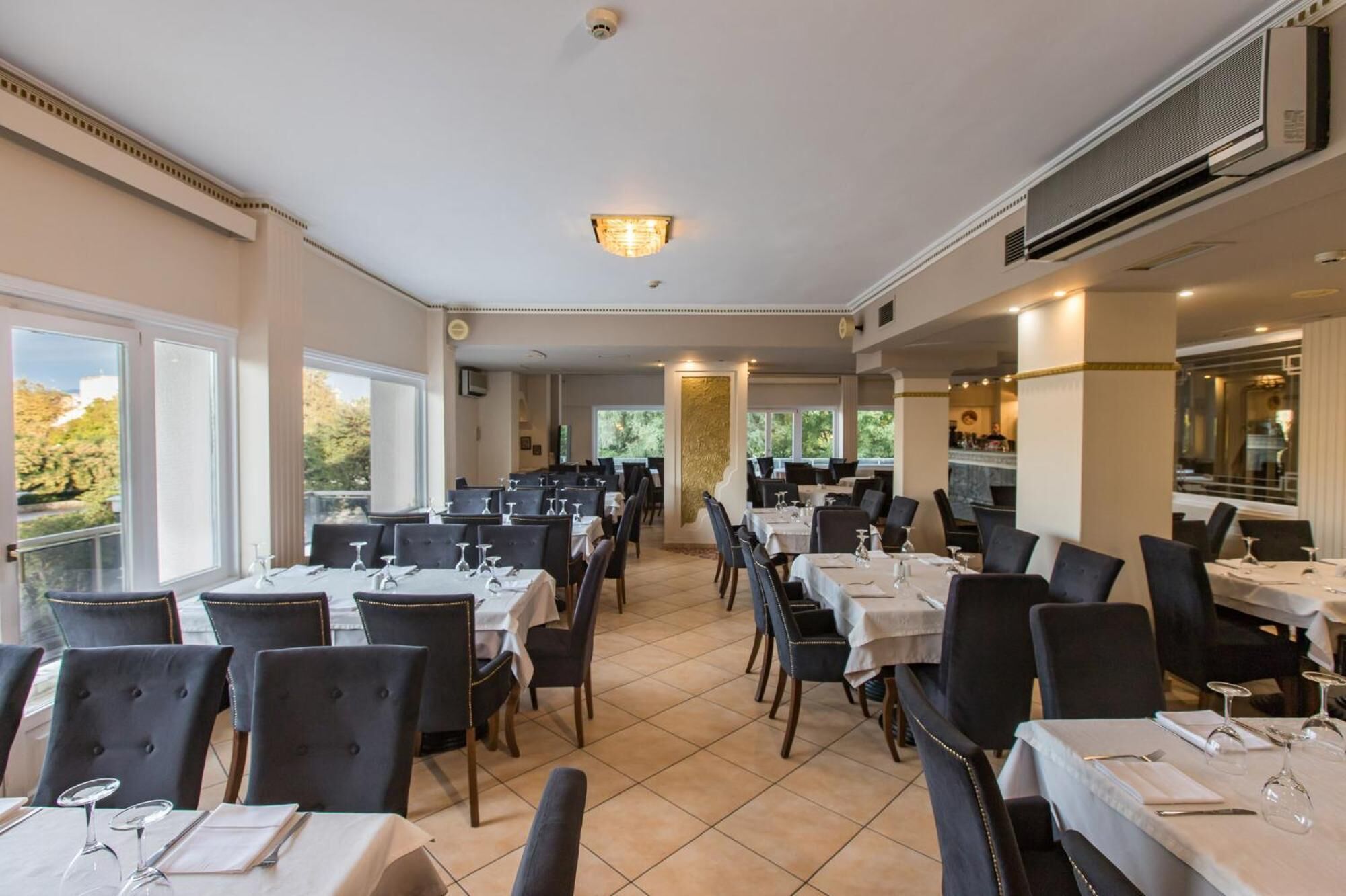 Ein Restaurant mit mehreren Tischen und Stühlen, großen Fenstern und einer Decke mit Einbuchtungslichtern.