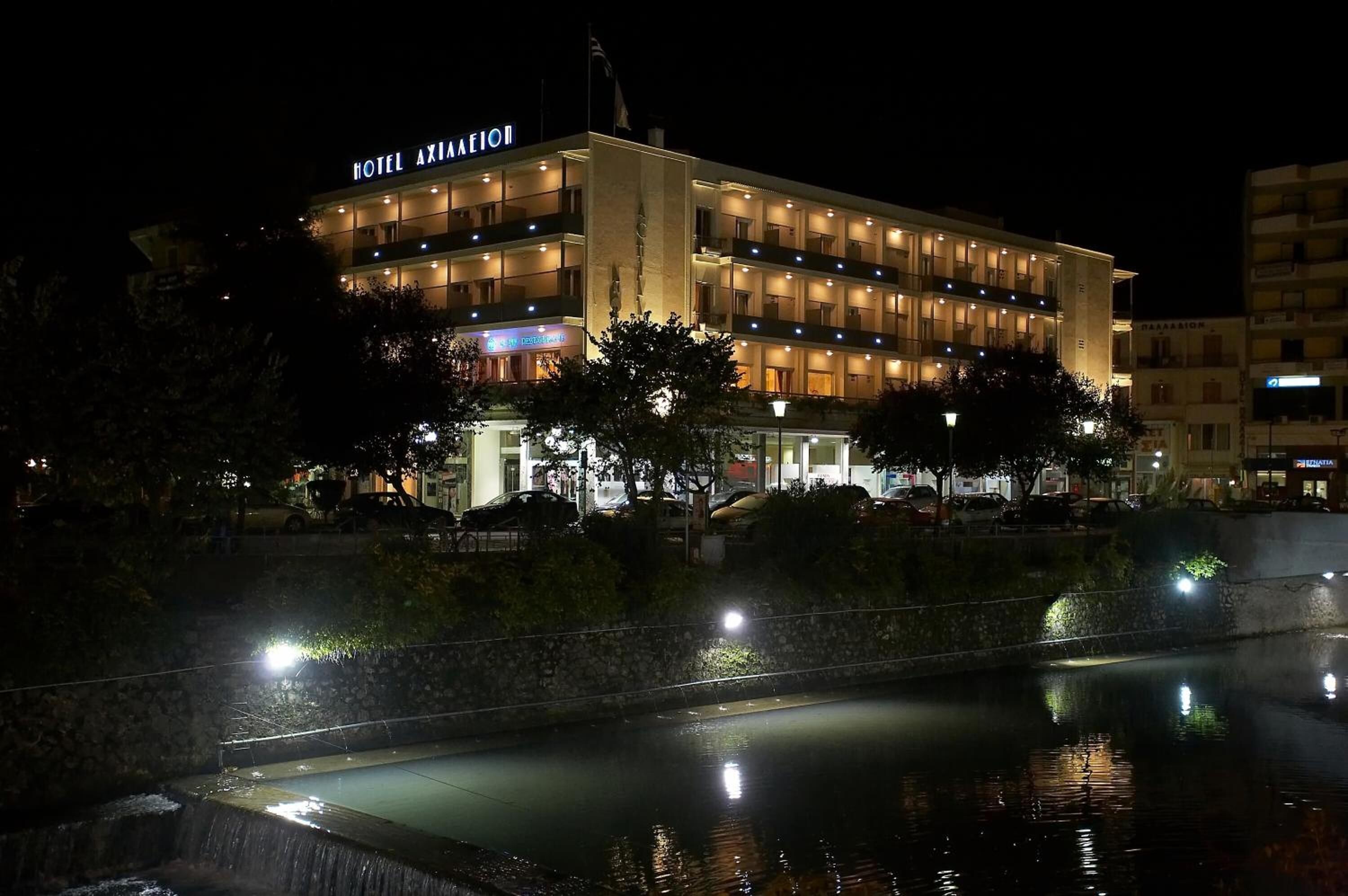 A multi-story hotel with a prominent sign, a reflective pool, and a well-lit facade.