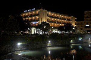 Un hotel de varios pisos con un letrero llamativo, una piscina reflectante y una fachada bien iluminada.