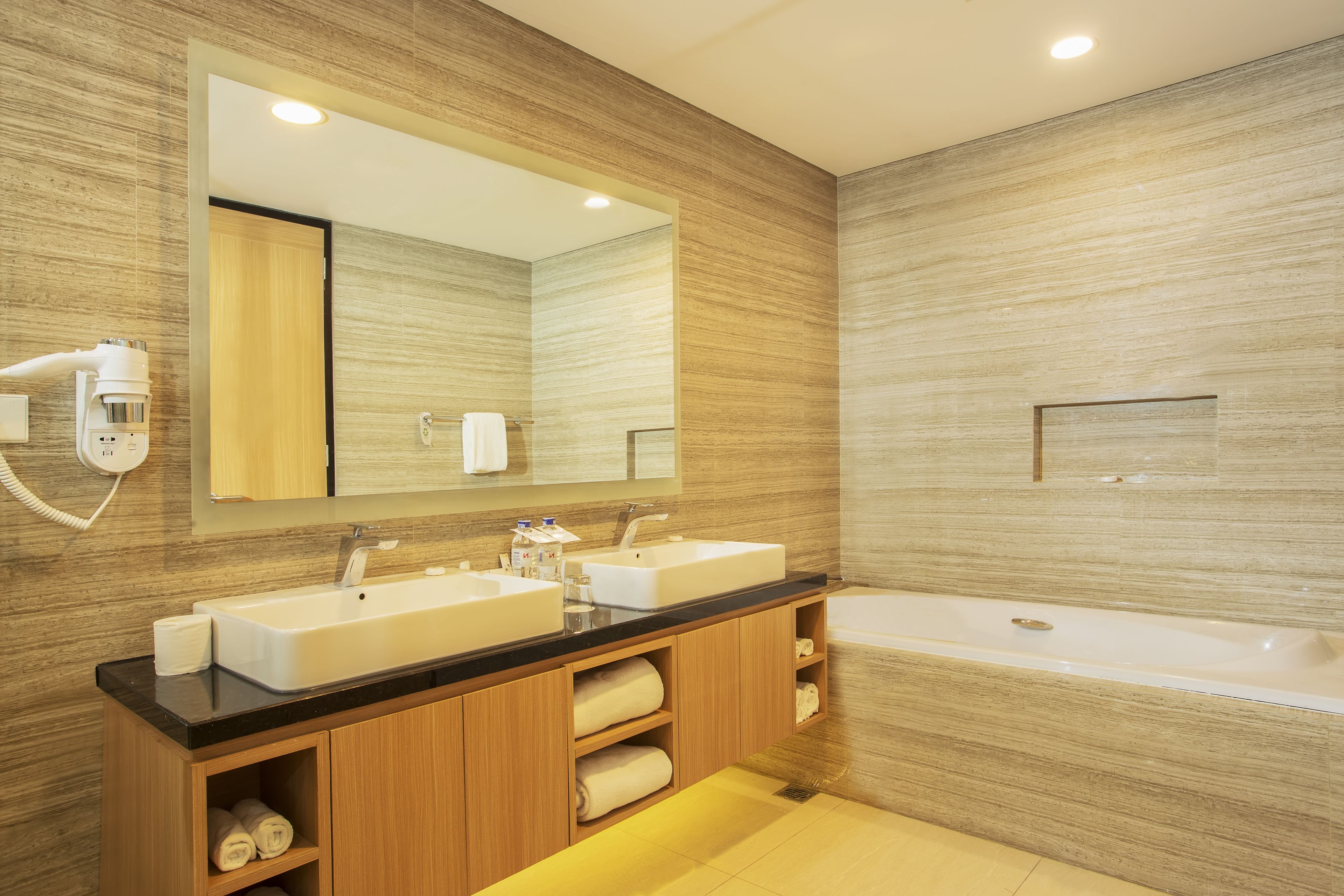 Une salle de bain moderne avec deux lavabos, un grand miroir et une baignoire.