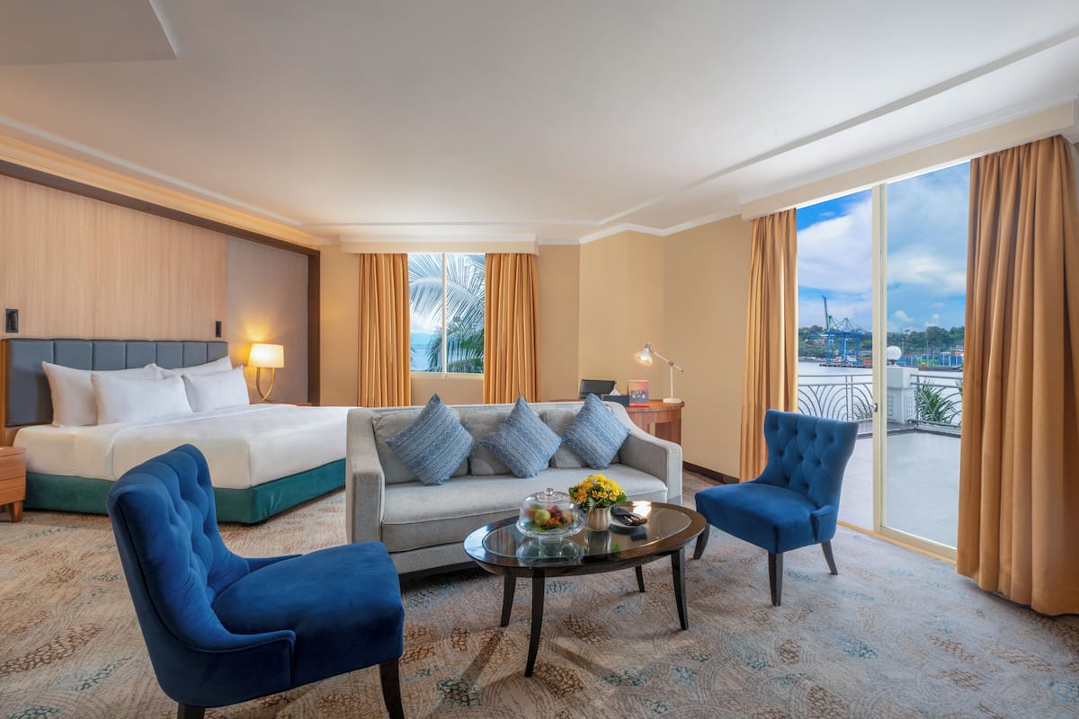 Ett hotellrum med en säng, en soffa, två fåtöljer, ett soffbord och utsikt över staden.