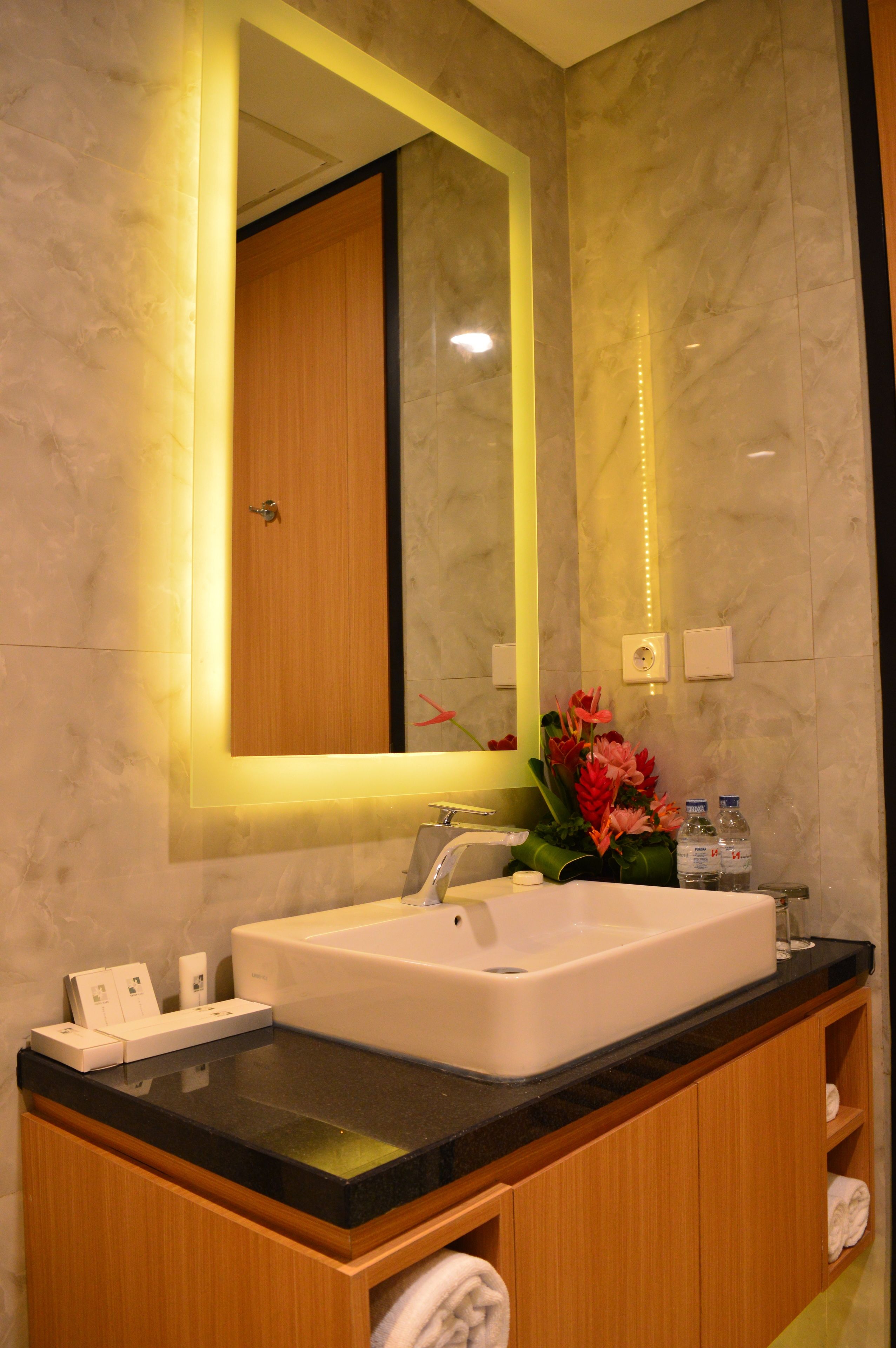Un baño con un espejo grande, un lavabo blanco y armarios de madera.