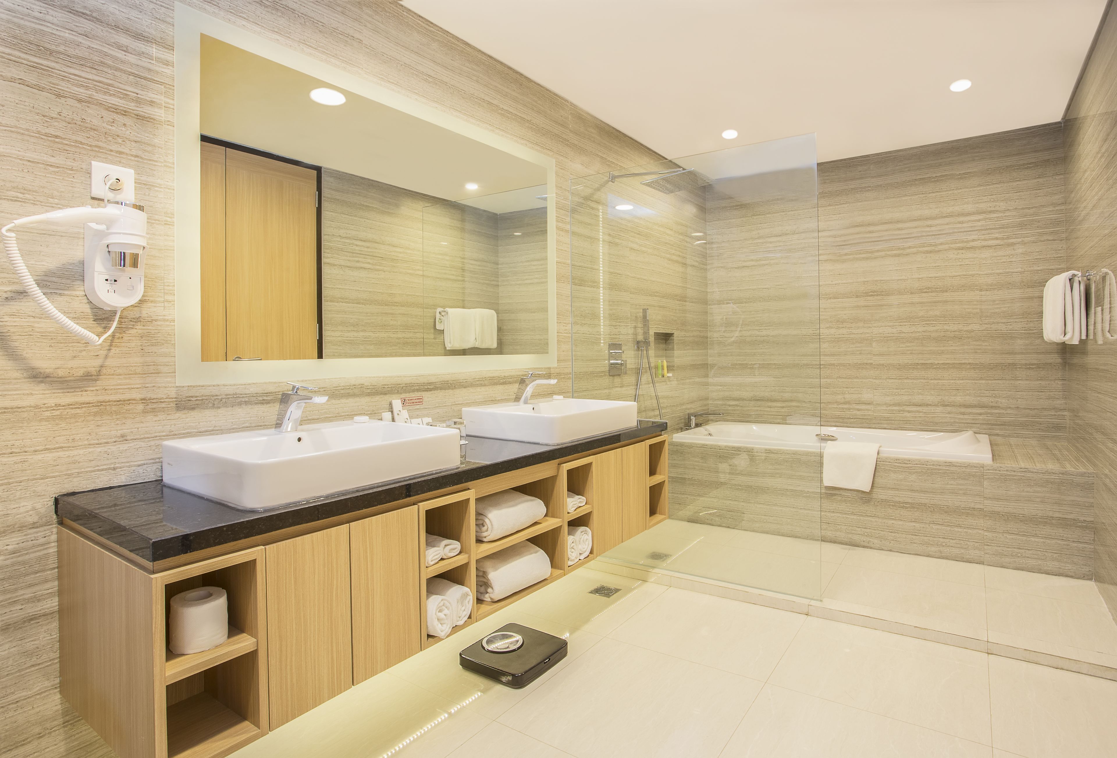 A modern bathroom with two sinks, a large mirror, a glass-enclosed shower, and a built-in toilet.