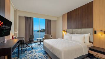 A hotel room with a bed, desk, chair, and a TV displaying the hotel name.