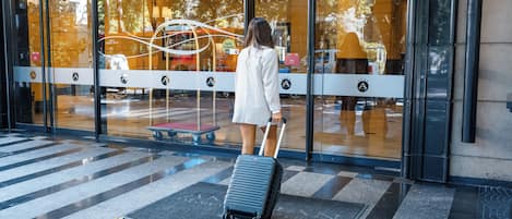 Una mujer con una maleta en la entrada del Hotel Americano Executive Menzo.