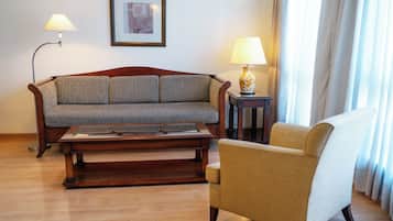 Ein Wohnzimmer mit Sofa, Sessel, Couchtisch, Lampen und einem gerahmten Bild an der Wand.