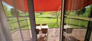 Enjoy a patio with a table and chairs, overlooking a well-maintained lawn and distant field.