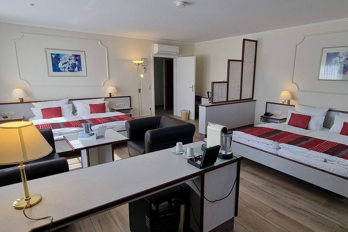 Une chambre d’hôtel avec deux lits, un bureau, une chaise, un canapé et une machine à café.