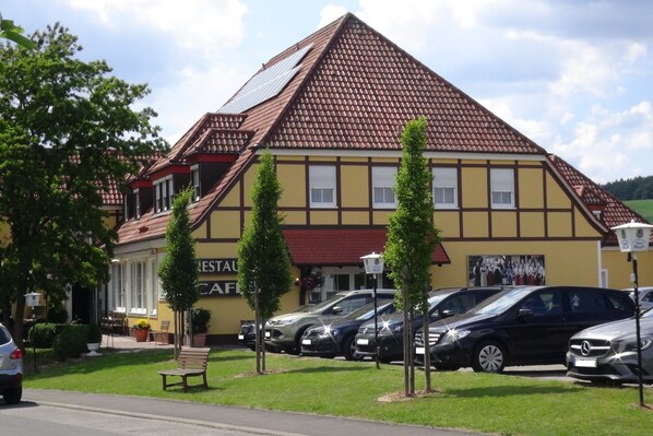 Traditional building with a steeply pitched roof, offering a charming outdoor setting with a well-maintained lawn and trees.