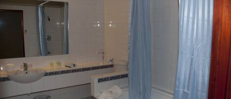A bathroom with a sink, mirror, bathtub, and shower curtain.