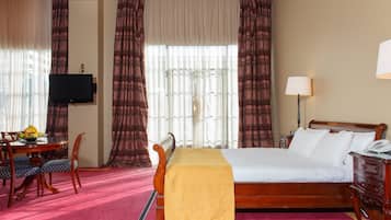 A hotel room with a bed, a desk with a chair, a television, and a lamp.