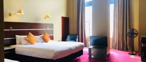 A hotel room with a large bed, a TV, a desk, and a chair.