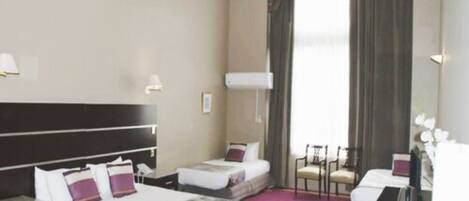 A hotel room with a large bed, a smaller bed, a desk, and a chair.