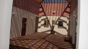 A room with a sloped ceiling, patterned floor, and two windows with curtains.