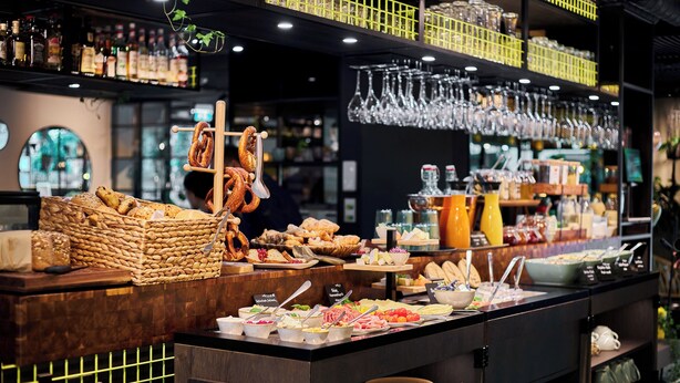 A buffet area with various food items, utensils, and glassware. - Cocoon München Sendlinger Tor (Munich)