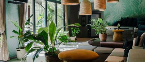 A modern lounge area with comfortable seating, large windows, and hanging woven light fixtures.