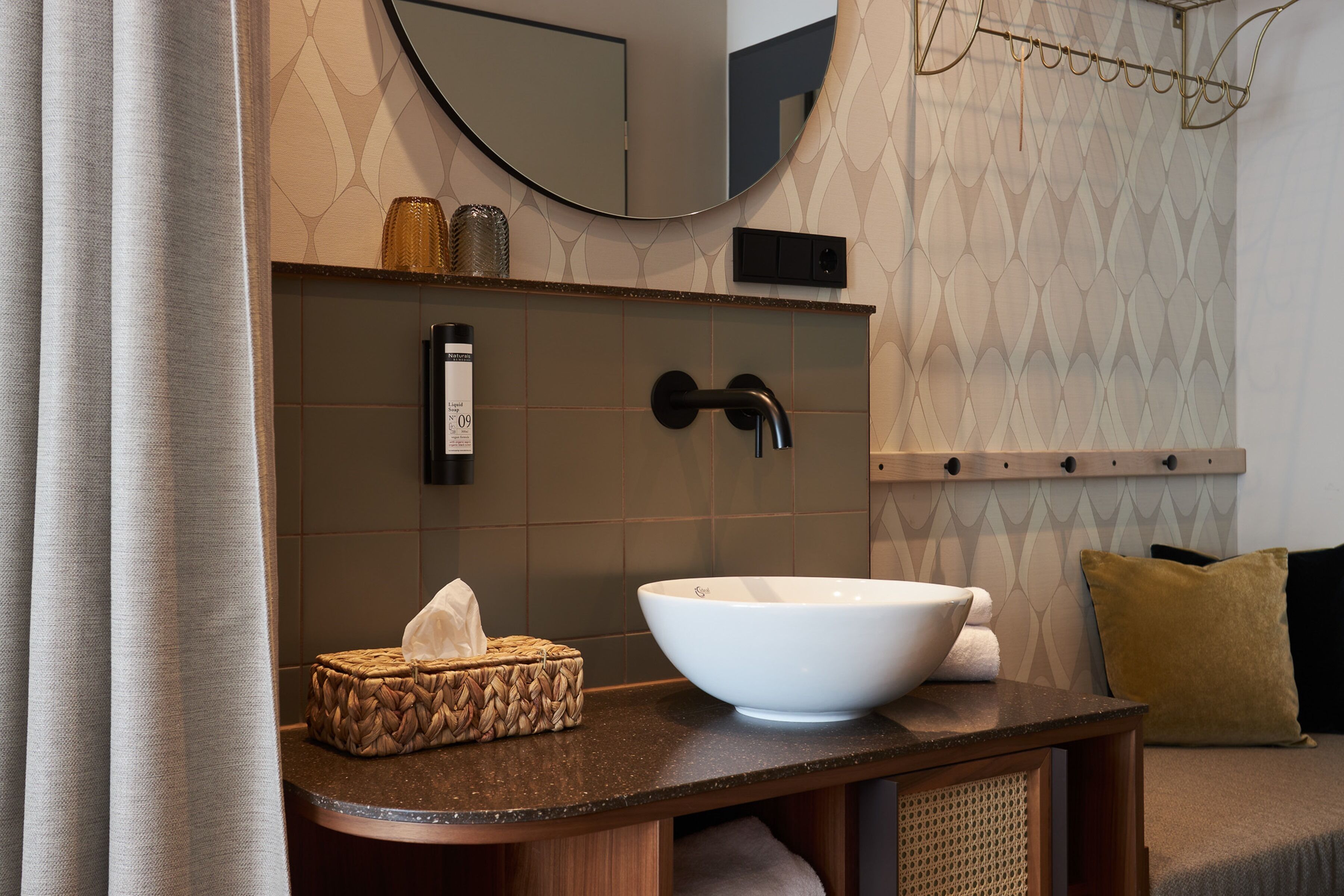 A bathroom with a large white sink, a mirror, and a towel rack.