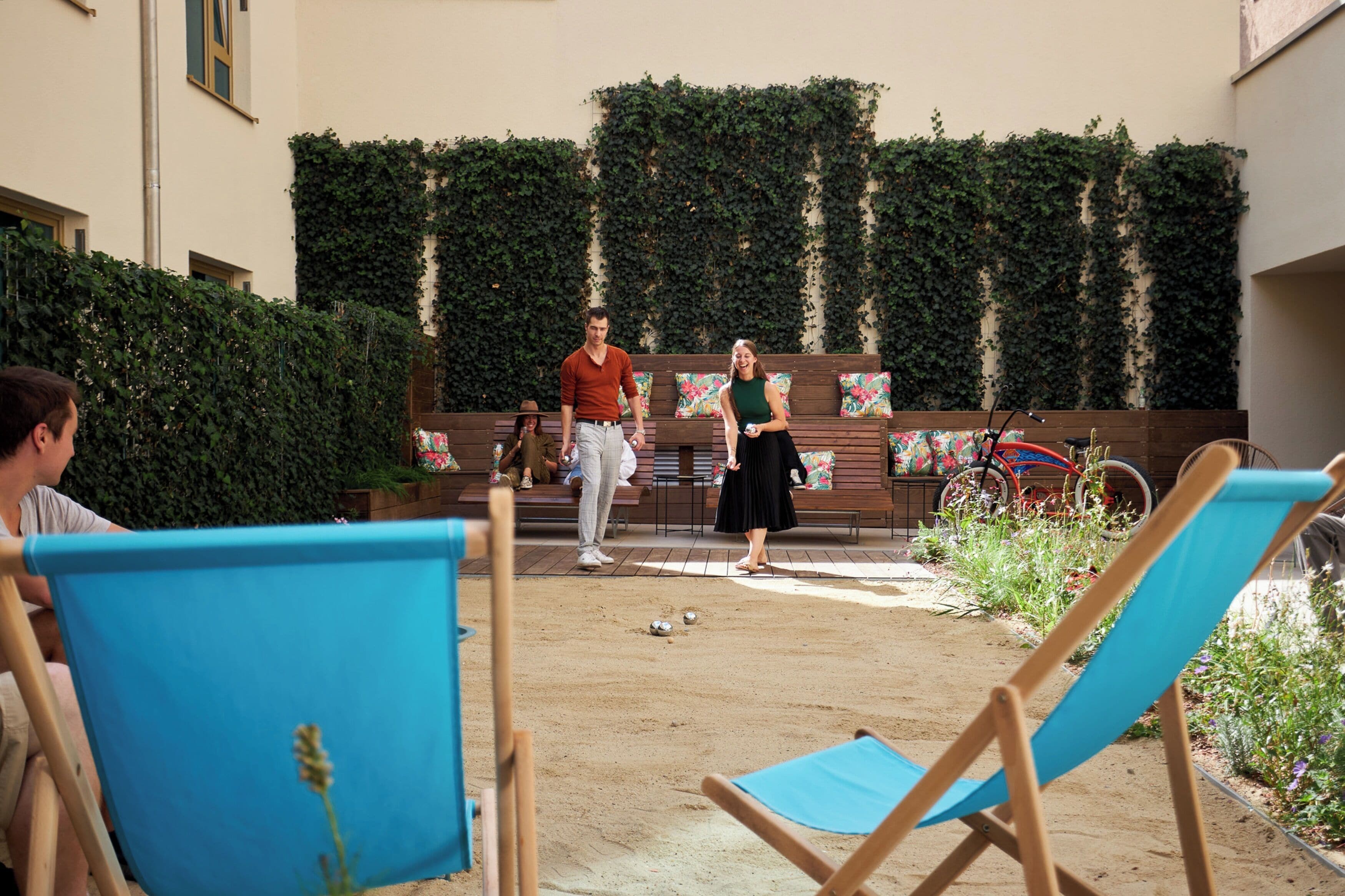 Ein Innenhof mit einem Sandvolleyballplatz, Bänken und einem Fahrrad.