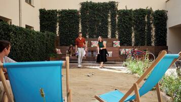 Ein Innenhof mit einem Sandvolleyballplatz, Bänken und einem Fahrrad.