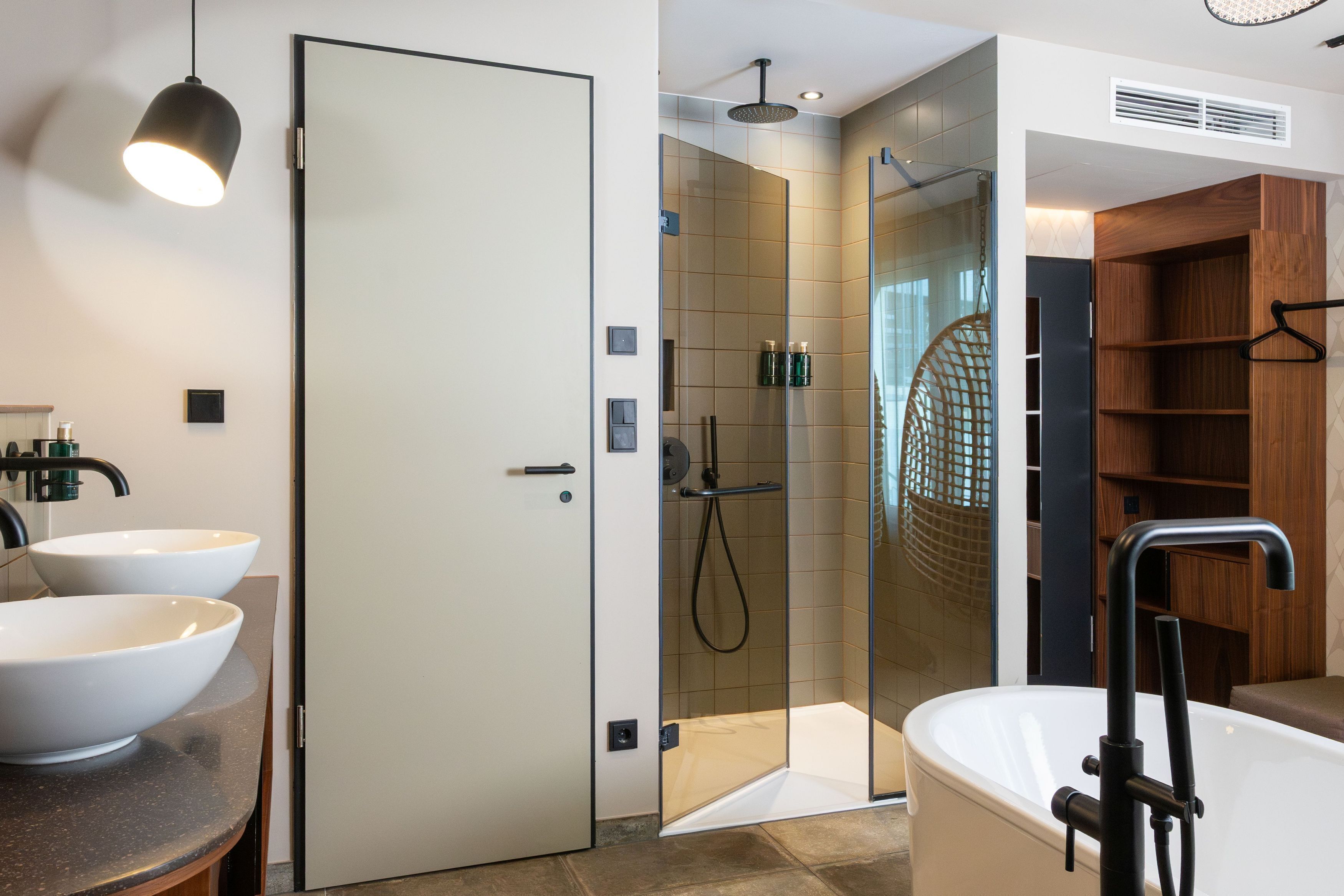 A modern bathroom with a glass-enclosed shower, a freestanding bathtub, and two white sinks.