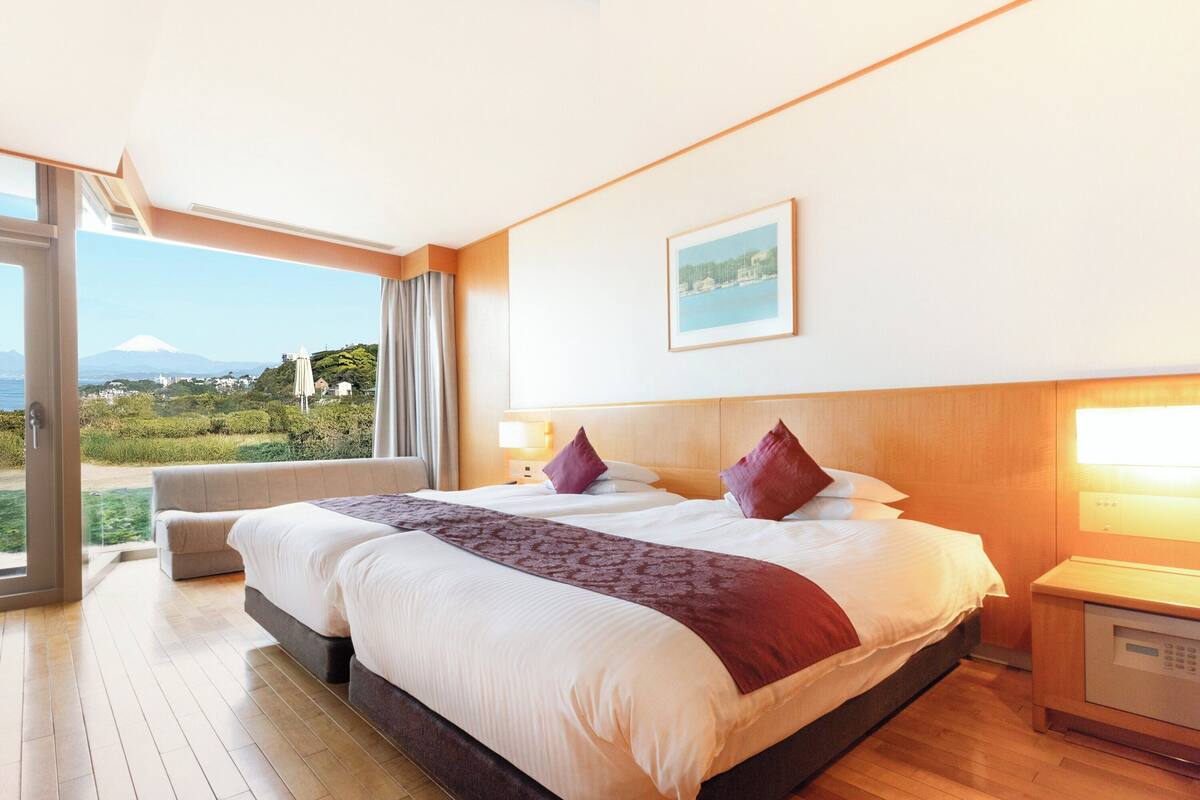 A hotel room with a large bed, a view of a mountain, and a sliding glass door leading to a balcony.