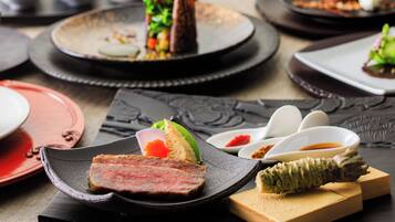 Una varietà di piatti su un tavolo, tra cui carne, verdure e un alimento dalla forma conica.